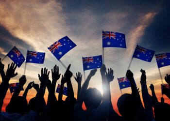 Crowd silhouetted in sunset wave Australian flags (image: Rawpixelimages/Dreamstime.com)