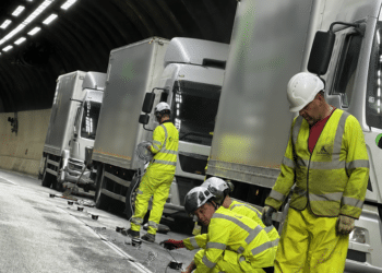 Workmen in hi-viz replace light studs in road in tunnel, with three white trucks in background (image: Clearview Intelligence)